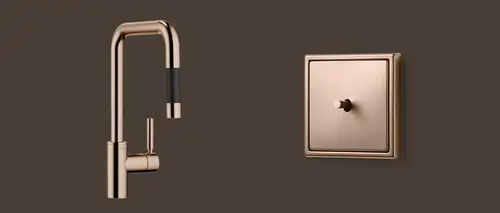 Schalter LS 1912 mit Kipphebel in Bronze gebürstet und die Küchenarmatur Meta Square von DORNBRACHT. Aufnahme in leichter Perspektive.