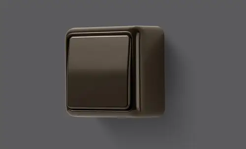 Bouton-poussoir dans le programme CD 500 en saillie en marron, pris en légère perspective sur un fond gris.