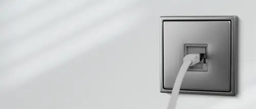 Anschlussdose im Schalterprogramm LS 990 aus Edelstahl. Ambienteaufnahme in Perspektive mit Netzwerkkabel.