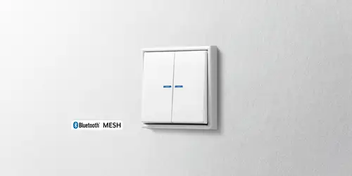 Pulsador JUNG HOME de la serie LS 990 en blanco, vista detallada en perspectiva luminosa.