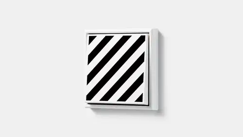 Drukknop in de LS 990-serie in wit met zwarte diagonale strepen, JUNG Unique x Studio Komo.