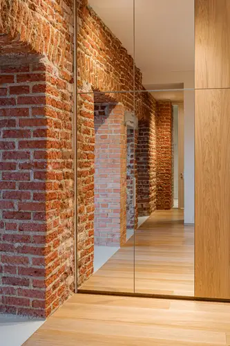 Ambient shot in a private residence in Vilnius. Section of a room with a brick passageway, photographed in the mirrored door of a built-in wardrobe.