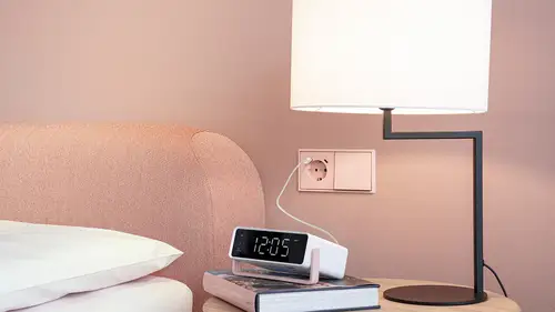 USB-Steckdose im Programm LS 990 in Les Couleurs® Le Corbusier, LC-32112 l‘ocre rouge clair kombiniert mit einem Schalter. Ambienteaufnahme in einem Schlafzimmer mit Nachttischlampe.
