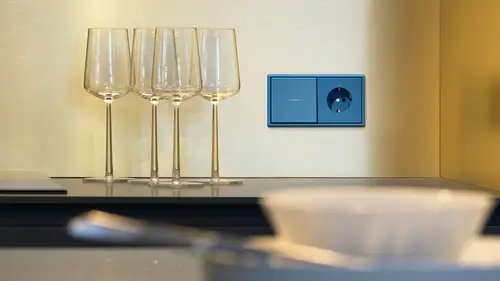 Lichtschalter mit Steckdose im Programm Les Couleurs® Le Corbusier in LC-32030 bleu céruléen 31. Ambienteaufnahme mit einem Esstisch und Weingläsern