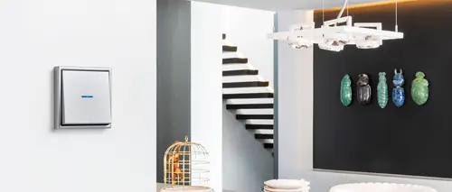 Lichtschalter mit Kontrollleuchte im Programm LS 990 in Aluminium. Ambienteaufnahme in einem Wohnraum.