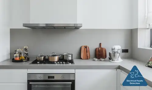 Photo of a kitchenette with oven, gas hob and food processor and the symbol for electrical fault detection.