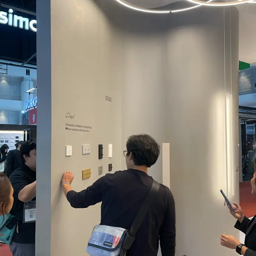 People looking at various JUNG products at the trade fair stand.