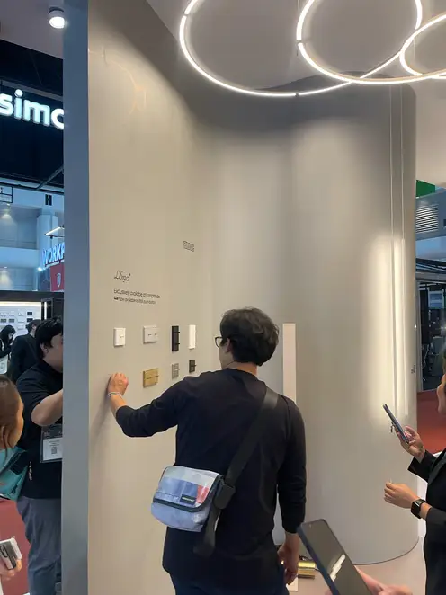People looking at various JUNG products at the trade fair stand.