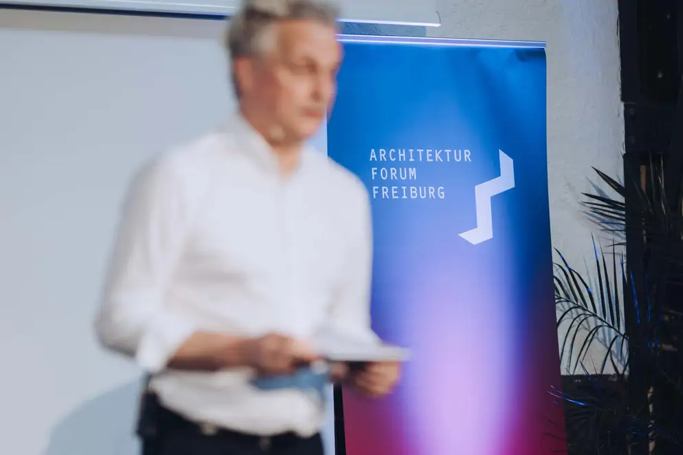 Architekturgespräche in Freiburg 2024, Moderator neben Logo "Architekturforum Freiburg"