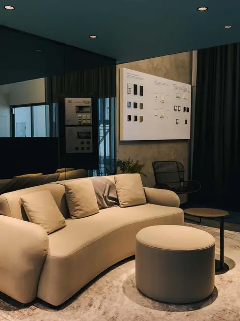 Brandstore Kuala Lumpur, Sitzecke mit beigefarbener Couch vor schwarzer spiegelnder Wand neben Präsentationsdisplay