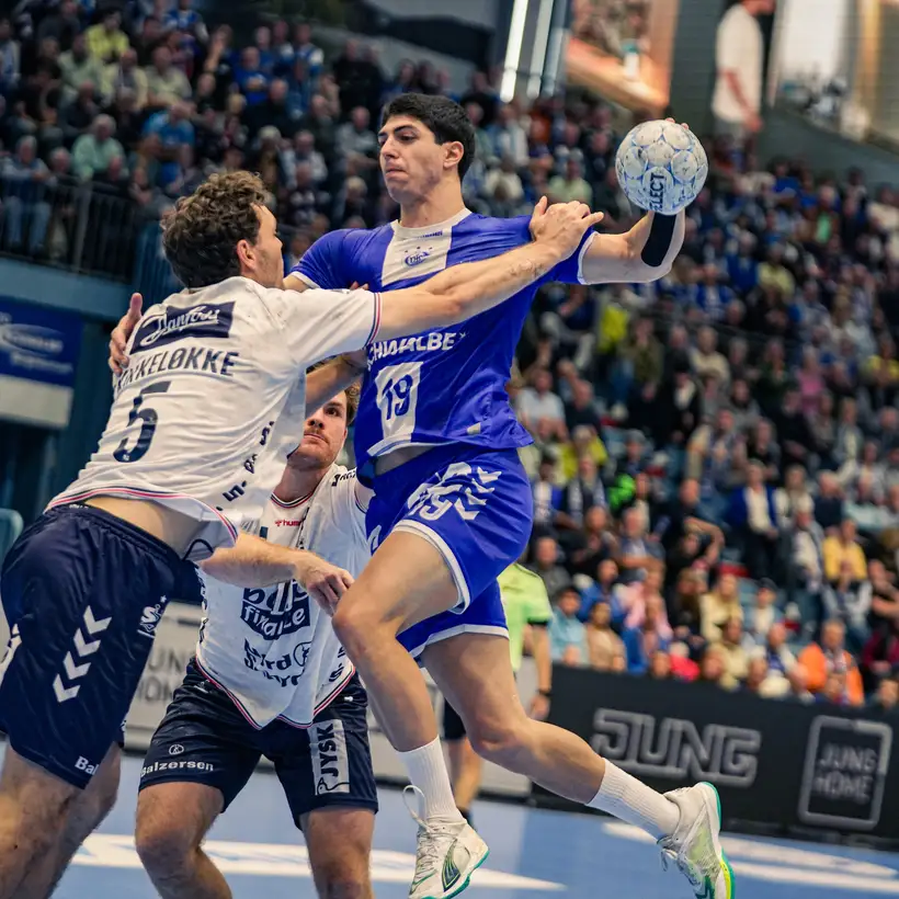 Handball-Spielszene zwischen dem VfL Gummersbach und Flensburg. Der Spieler des VfL ist in Ballbesitz und halb im Sprung.