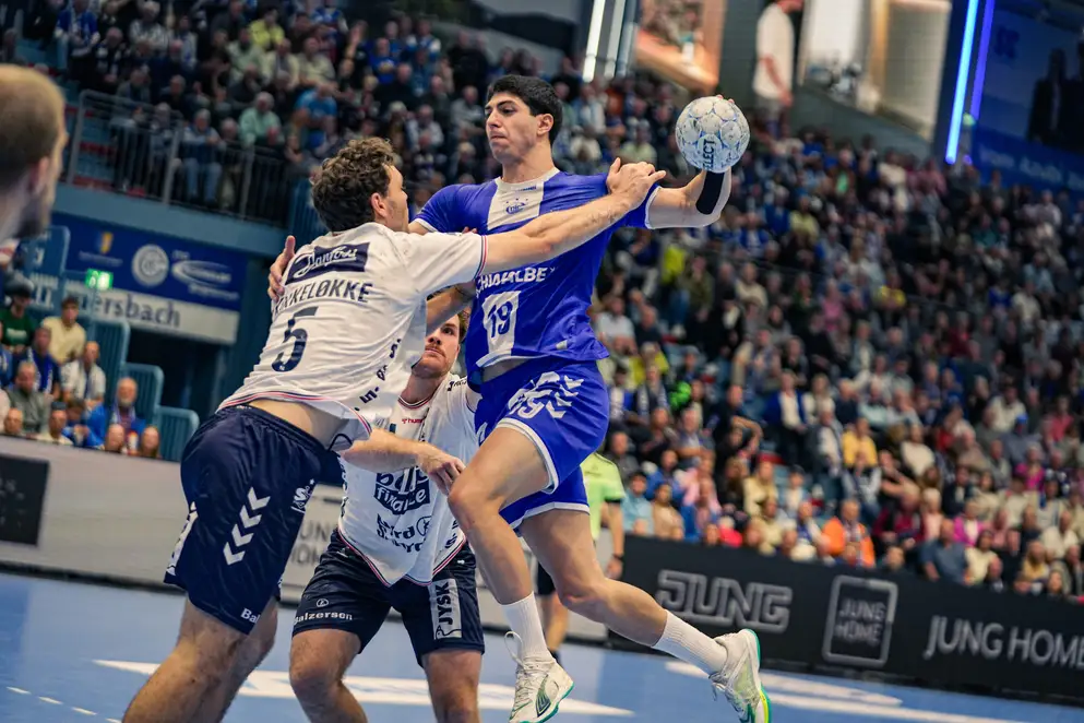 Handball-Spielszene zwischen dem VfL Gummersbach und Flensburg. Der Spieler des VfL ist in Ballbesitz und halb im Sprung.