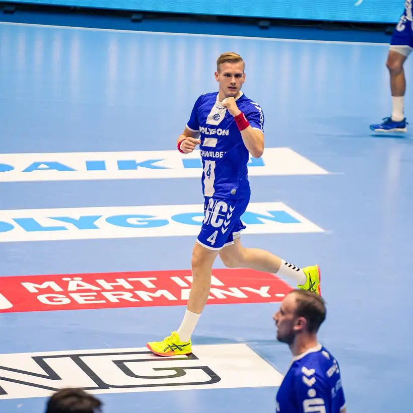 Ein Spieler des VfL läuft mit geballter Faust über das Spielfeld. Auf dem Boden sind verschiedene Sponsoren-Logos zu sehen.