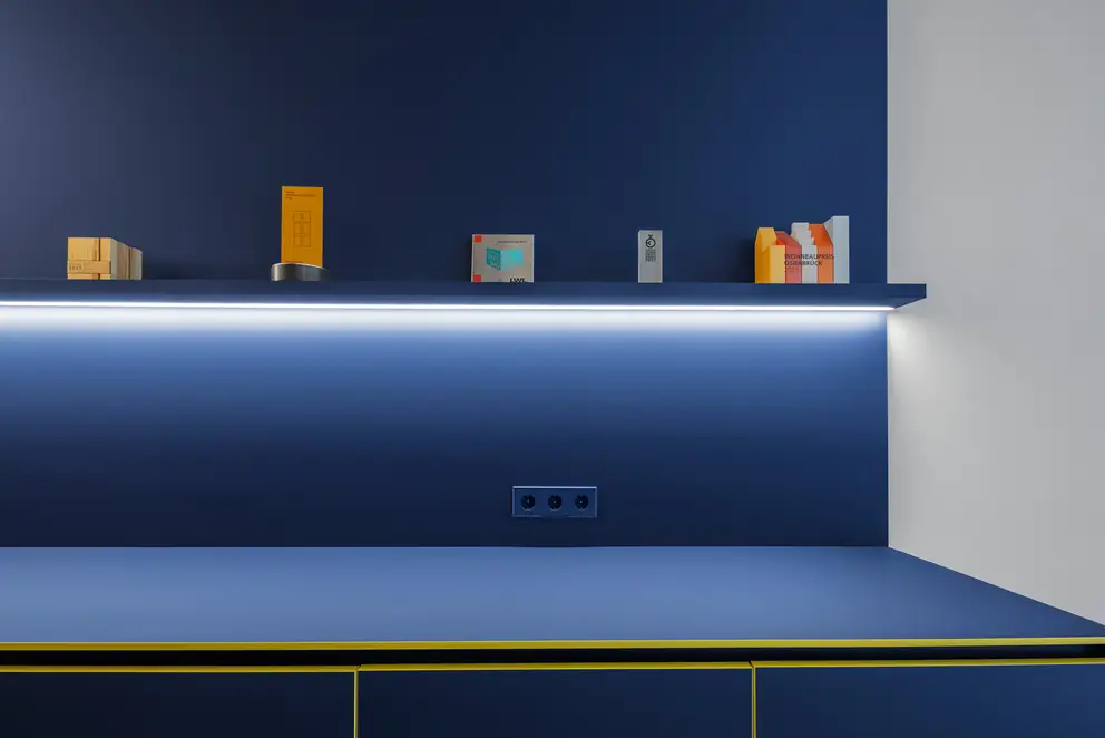 Ein blaues Sideboard mit LS 990 Steckdosen in passendem Les Couleurs Farbton