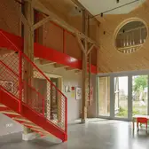 Innenansicht der renovierten Scheune mit einer großen roten Metalltreppe