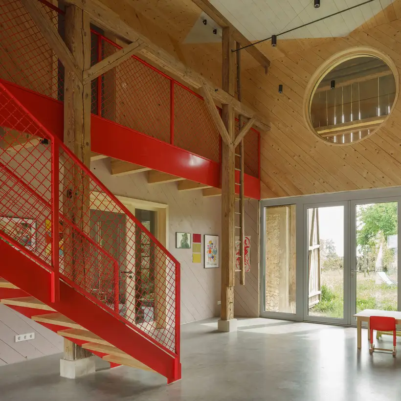 Innenansicht der renovierten Scheune mit einer großen roten Metalltreppe