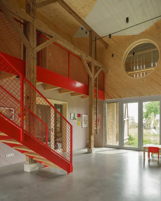 Innenansicht der renovierten Scheune mit einer großen roten Metalltreppe