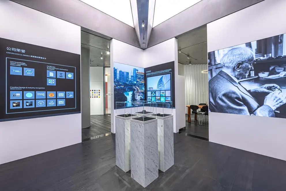 JUNG Showroom Cimen Shanghai / Ausstellungs-Räumlichkeiten mit zentral gehaltenen Produkt-Präsentationssäulen umgeben von großflächigen Fotos