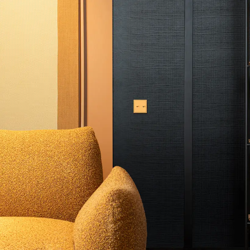 Lichtschalter im Programm LS 1912 in Les Couleurs® Le Corbusier in leichter Perspektive. Detailaufnahme mit einem Sessel und Bücherregal im Anschnitt.