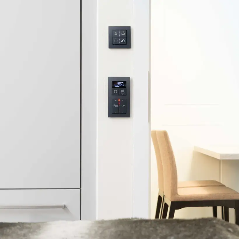 KNX F40 Taster im Programm A Creation aus Kunststoff in Schwarz, frontal fotografiert im Raumausschnitt, Referenzobjekt SI-Suites Stuttgart.