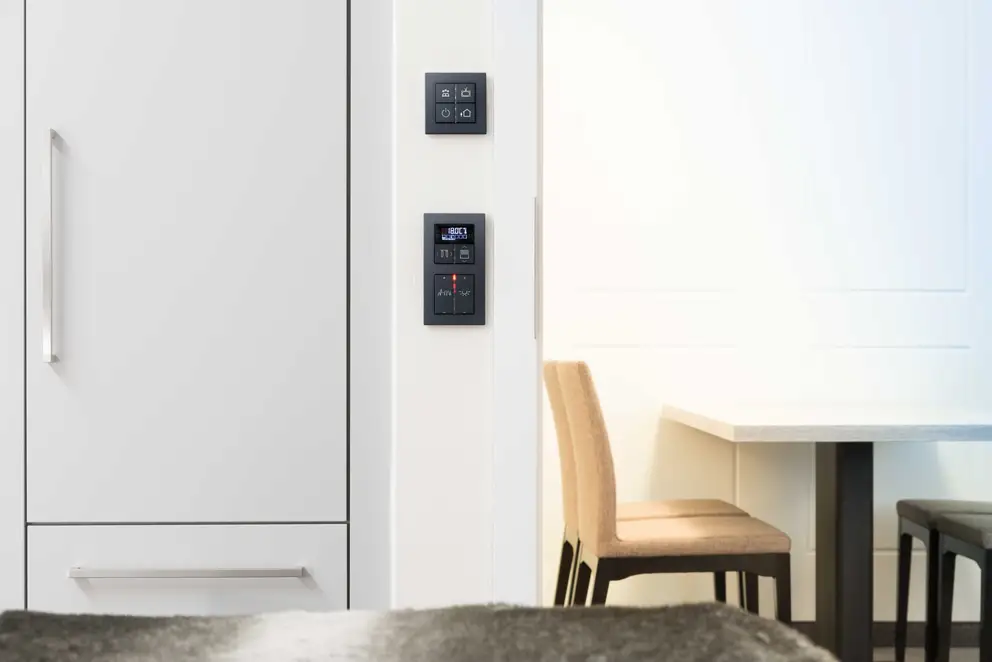 KNX F40 Taster im Programm A Creation aus Kunststoff in Schwarz, frontal fotografiert im Raumausschnitt, Referenzobjekt SI-Suites Stuttgart.