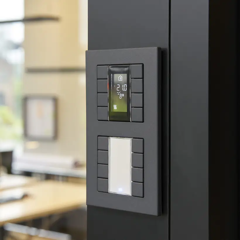 Taster F 50 für KNX und eNet SMART HOME als 4fach Taster, Detailaufnahme in leichter Perspektive, aufgenommen vor einer schwarzen Wand. Linksseitig ist der Hintergrund verschwommen.