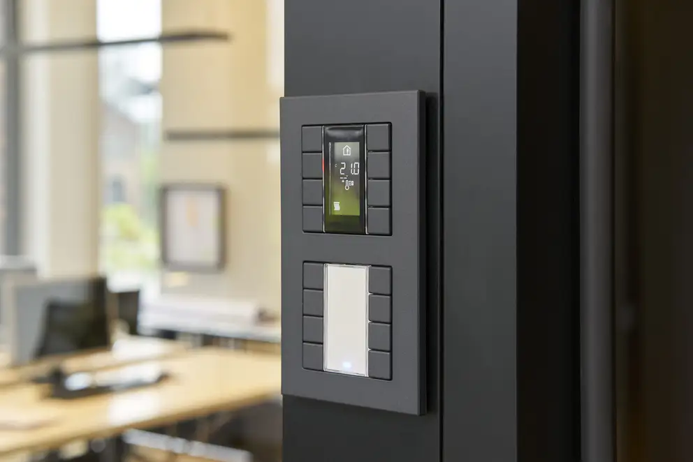 Taster F 50 für KNX und eNet SMART HOME als 4fach Taster, Detailaufnahme in leichter Perspektive, aufgenommen vor einer schwarzen Wand. Linksseitig ist der Hintergrund verschwommen.