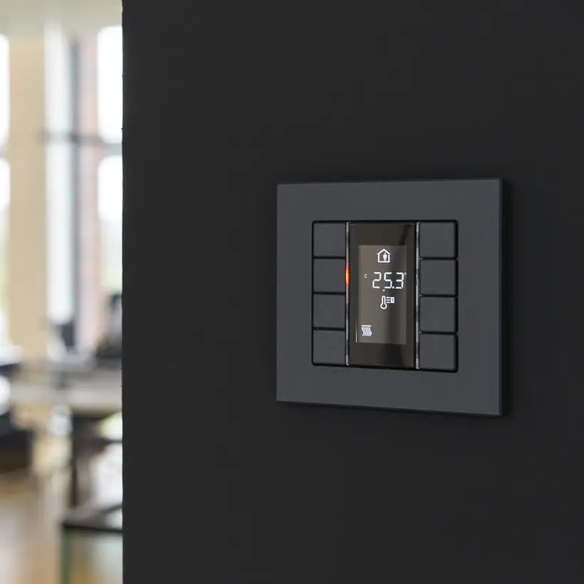 Taster F 50 für KNX und eNet SMART HOME als 4fach Taster, Detailaufnahme in einem schwarz gestrichenem Durchgang, durch geringe Tiefenschärfe hat der Hintergrund eine starke Unschärfe.