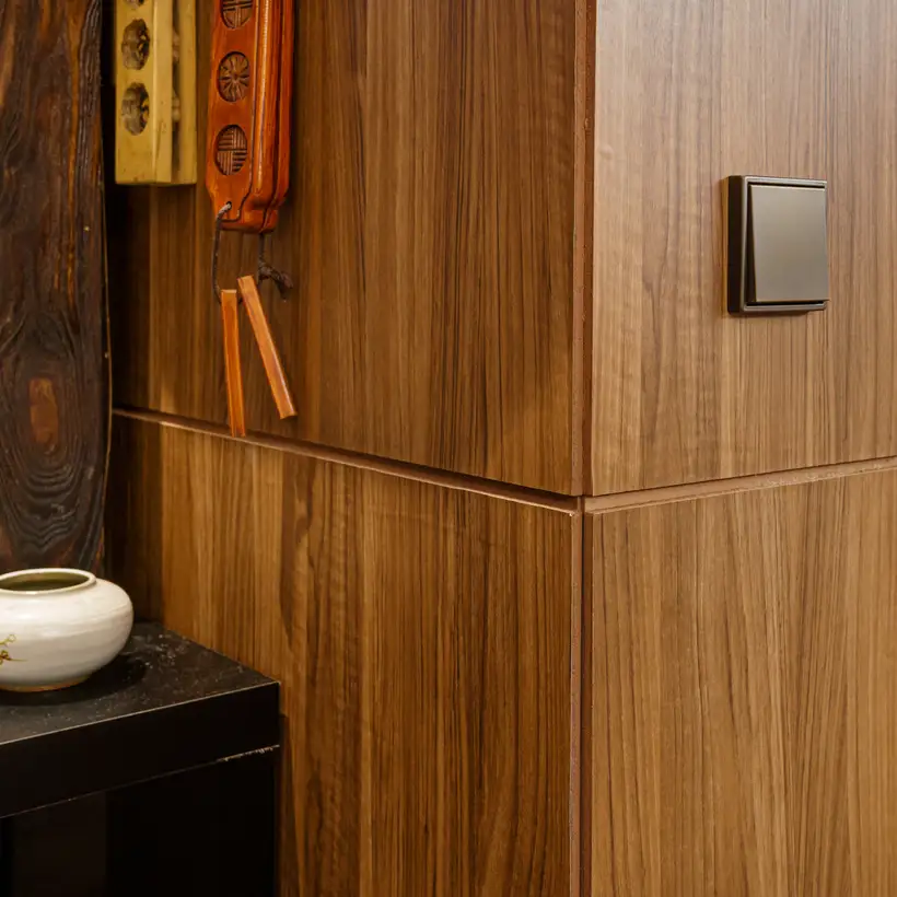 Taster im Programm LS 990 in Messing Antik, aufgenommen in Perspektive, vor einem mit Holz verkleidetem Durchgang. Linksseitig befinden sich asiatische Teekannen weiter hinten im Raum.
