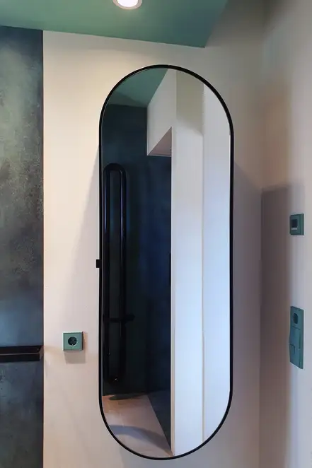 LS 990 Taster und Schuko Steckdosein Les Couleurs® Le Corbusier in 32041 vert anglais clair, fotografiert vor einer rosa Wand im Badezimmer,Raumausschnitt.