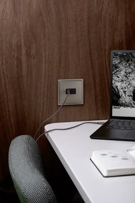 LS 990 USB-Ladegeräte aus Edelstahl mit Anschlüssen für USB Typ A und Typ C, an einem Schreibtisch und gerade angeschlossenem Laptop im Ausschnitt