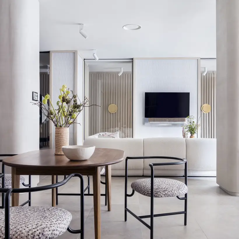 JUNG Brandstore Madrid, Esstisch vor Wohnbereich mit heller Couch und Flachbildfernseher