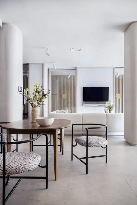 JUNG Brandstore Madrid, Esstisch vor Wohnbereich mit heller Couch und Flachbildfernseher